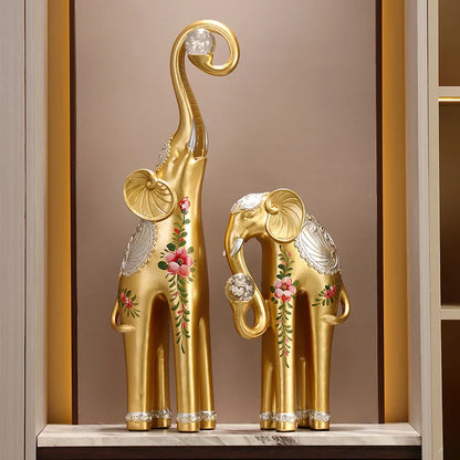 Decorative gold elephant statues with floral designs on a shelf.