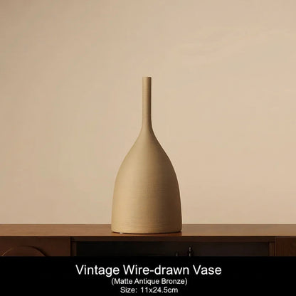Matte Antique Bronze Beige vase on a wooden surface with a beige background