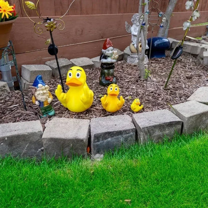 Garden scene with rubber ducks and gnomes on a stone border.