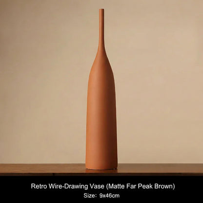 Matte Far Pearl Brown Terracotta-colored vase on a wooden surface with a beige background