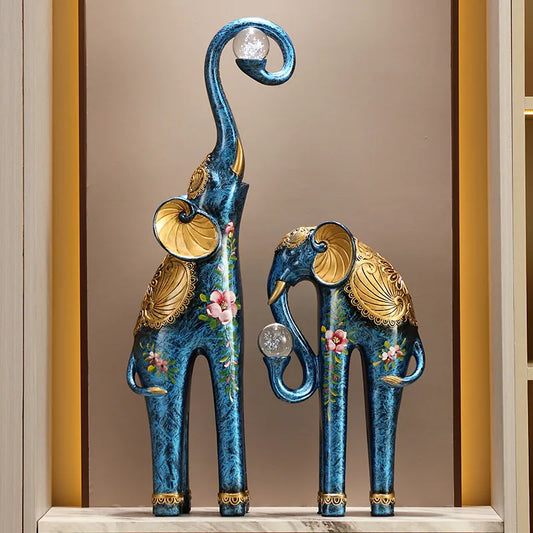 Decorative blue elephant statues with gold accents on a shelf.