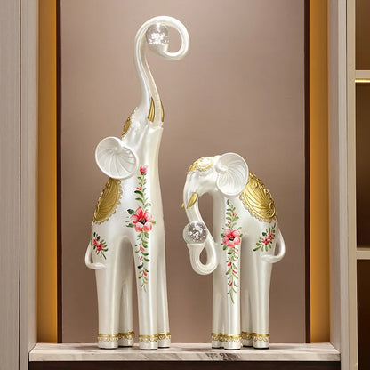 Decorative elephant statues with floral designs on a shelf against a brown wall.